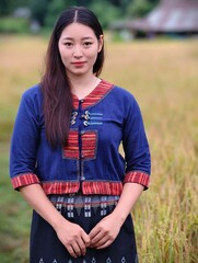 Portrait of young Asian woman in traditional Thai outfit standing in rice field countryside, representing beauty, simplicity and Thai rural lifestyle.