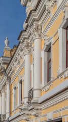 Facade fragment of an old mansion in an eclectic style with rich stucco moldings and columns. An elegant architectural background for the concept of luxury, culture, and history.
