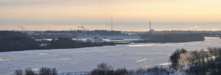 Panoramic winter background with frozen river and high voltage tower at the distance, winter industrial view, energy supply in winter concept