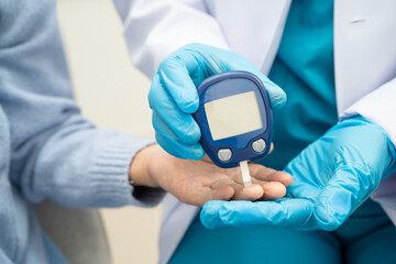 Asian doctor using digital glucose meter for check sample blood sugar level to treatment diabetes.