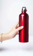 A red bottle is held gently by hand against a white background, creating a bold and striking...