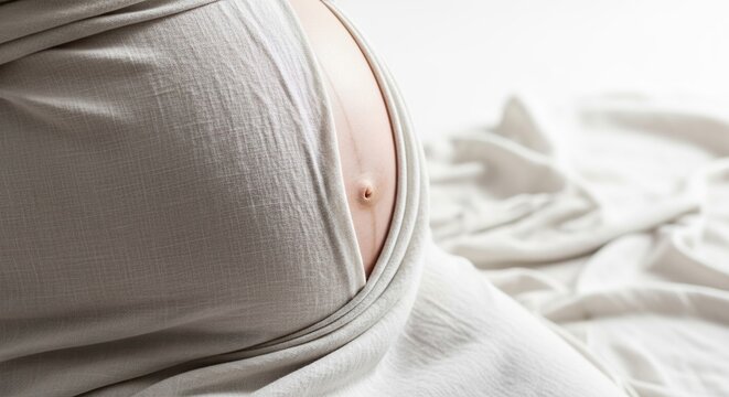Pregnancy belly close up maternity photoshoot with white fabric background for motherhood concept