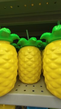 Plastic pineapple-shaped cups with green lids and straws sitting on a store shelf
