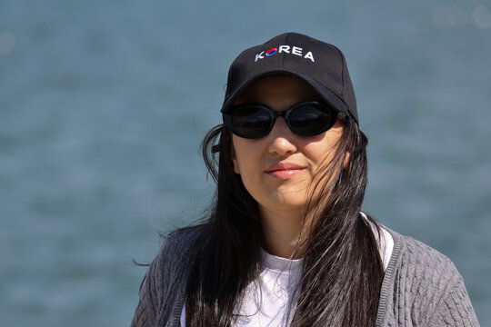 Korean woman proudly wearing a cap with Korea and its flag symbol, enjoying the outdoors