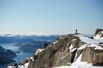 Hiker on Snowy Mountain Overlooking Fjord