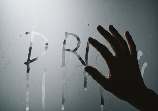 Silhouetted Hand Tracing Letters on Steamy Glass Surface