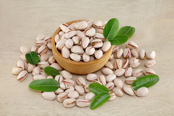 Pistachios spilled out of wooden bowl, close up
