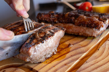 Hand carving juicy grilled picanha steak on rustic wooden board, preparing a traditional argentine barbecue meat meal, enjoying healthy delicious food