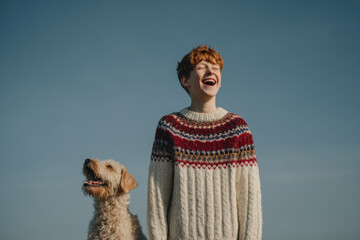joyful boy and his playful dog are sharing hilarious moment outdoors both wearing matching colorful sweaters