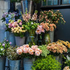 a beautiful flower shop display with pastel and cream-colored blooms arranged in metal buckets.