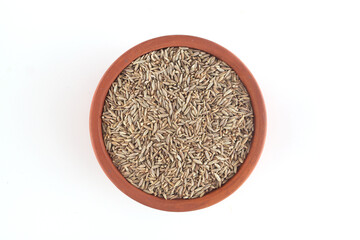 Fresh cumin seeds in clay bowl on white background