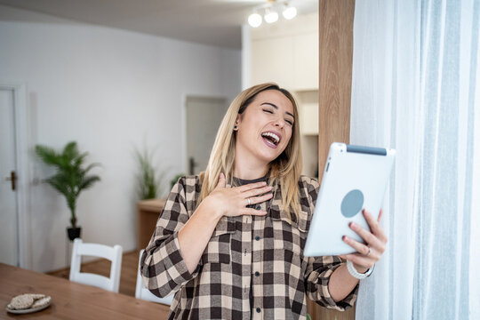 Woman laughing during video call on tablet at home