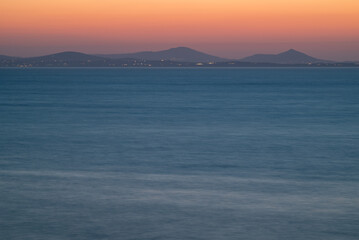 Fototapeta premium Serene Ocean Sunset with Distant Mountains