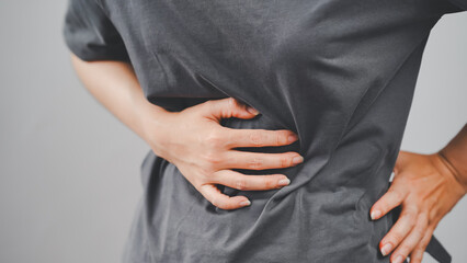Close-up of a person clutching their side, experiencing abdominal or kidney pain, suggesting health or internal organ issues.