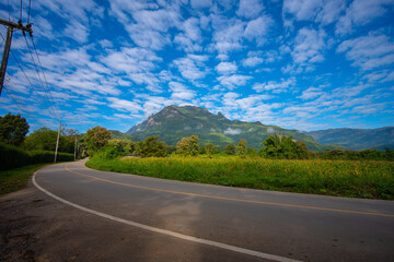 Winding road leads to Doi Luang Chiang Dao Mountain with lush green hill bright blue sky, Chiang Mai, Thailand