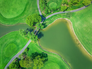 Aerial view of a green golf course with a bridge over the water.