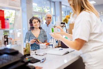 Woman buying medicine from female pharmacist in pharmacy.
