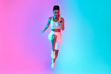 A fitness model executes a high knee exercise with a focused expression. The background features bright pink and blue colors, creating an energetic and motivating atmosphere perfect for workouts.