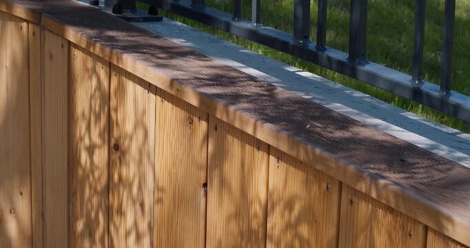Close-up of natural wooden cladding panels and modern metal fence in outdoor architectural landscaping.