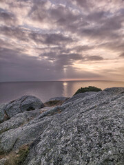 Fototapeta premium Rocky coastline at sunset with sun rays over ocean