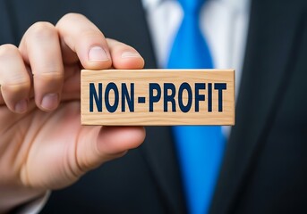 A person in a suit and tie holds a wooden block with the words nonprofit clearly printed in blue, symbolizing charitable organizations and social causes