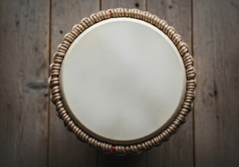 Top view of a djembe drum with a textured rope border on a wooden surface
