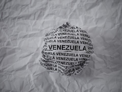 Crumpled paper ball with words Venezuela on a crumpled white paper background.