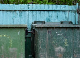 A close-up shot of old dumpsters near a metal fence.