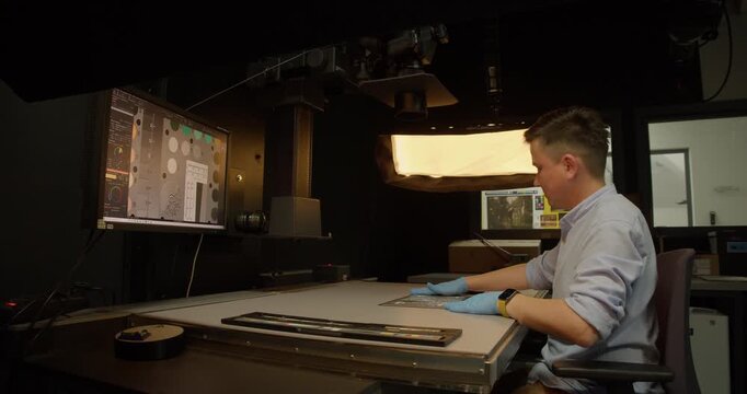 Archive and museum technician verifies digitization equipment, ensuring quality control in heritage digitalization and electronic records management.