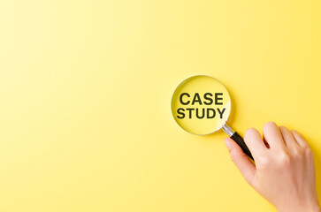 Case study research concept, hand holding magnifying glass focusing on bold text CASE STUDY over yellow background symbolizing detailed investigation, learning method and business or academic analysis