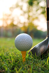 Golf Ball on a Tee at Sunset with Golf Club in Background