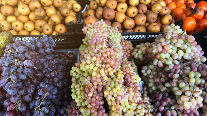 Fresh ripe grapes of different colors and pears displayed at outdoor market stall, symbolizing healthy lifestyle, organic farming, vegan food and natural nutrition for grocery and diet concepts