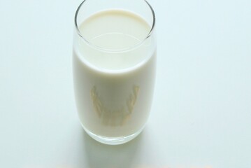 A tall glass of cold white milk on a light blue surface