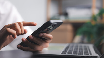 Person Using Smartphone with Laptop for Digital Communication and Online Work