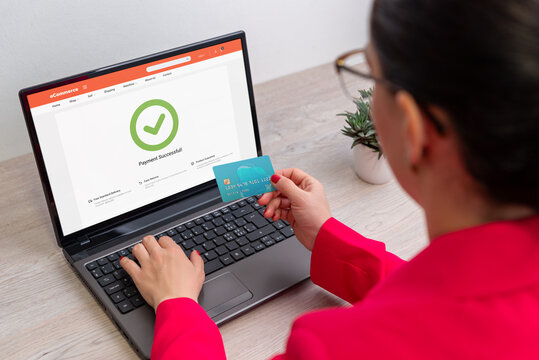 Woman completing online payment on laptop, holding credit card after successful transaction, concept of e-commerce, secure checkout, and digital business success