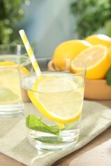 Refreshing water with lemons and mint on wooden table outdoors, closeup