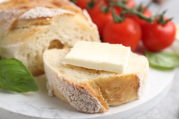 Slices of baguette with butter, basil and tomatoes on light grey table, closeup