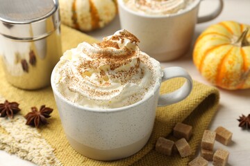 Tasty pumpkin latte with whipped cream, spices and fresh vegetables on white table, closeup