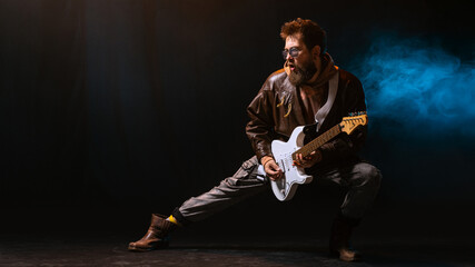 Electric guitarist playing solo in blue smoke with emotional expression. Concept of music streaming...