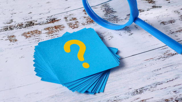 Question Mark Search: Stack of Blue Sticky Notes and Magnifying Glass on Wood