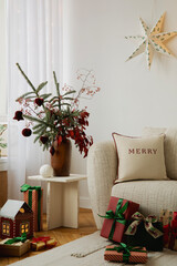 Cozy Christmas living room with gifts, a white sofa, and festive decor pillows.