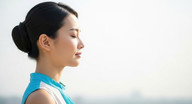 Serene young Asian woman meditating peacefully outdoors, embodying calm and inner balance for wellness and mindfulness content