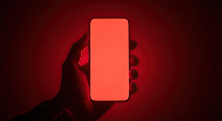 Grasping a glowing red smartphone screen in darkness, perfect for tech promotions and digital concepts