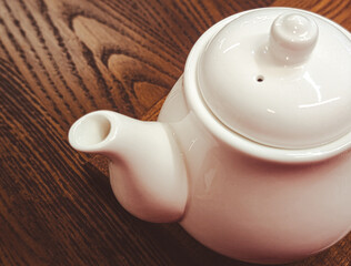 close up of a white ceramic teapot on a dark rustic wooden table background