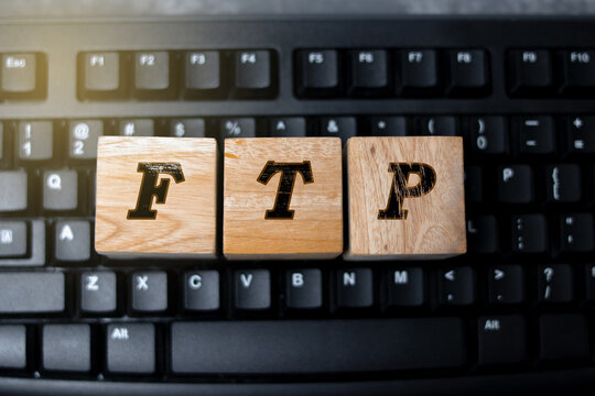 Wooden blocks displaying the letters “FTP” placed on a computer keyboard, symbolizing file transfer protocol, data exchange, and modern digital technology in a professional workspace setting.