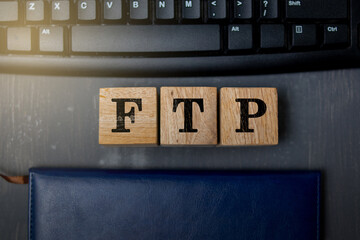 Wooden blocks displaying the letters “FTP” placed on a computer keyboard, symbolizing file transfer protocol, data exchange, and modern digital technology in a professional workspace setting.