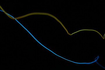 Abstract long exposure light painting with blue and yellow glowing lines, creating a sense of motion and energy on a black background.