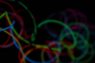 A chaotic, energetic scribble of multiple glowing EL wire lines in various colors, creating a...