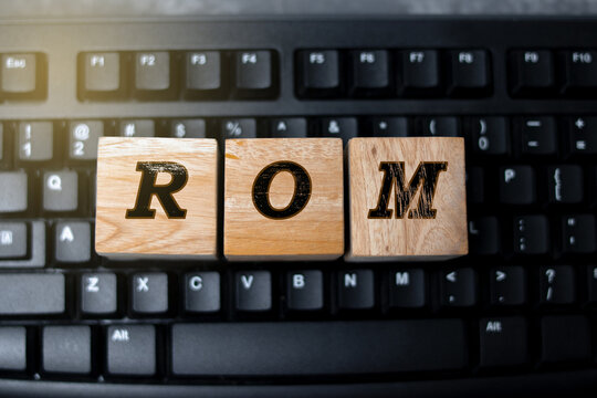 Wooden blocks with the letters ROM placed on a black computer keyboard, symbolizing computer memory, data storage, and technology concepts in modern digital systems.