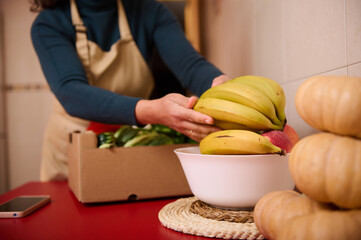 Homemade Kitchen Scene With Fresh Bananas, Pumpkins, And a Box Of Produce On a Red Counter